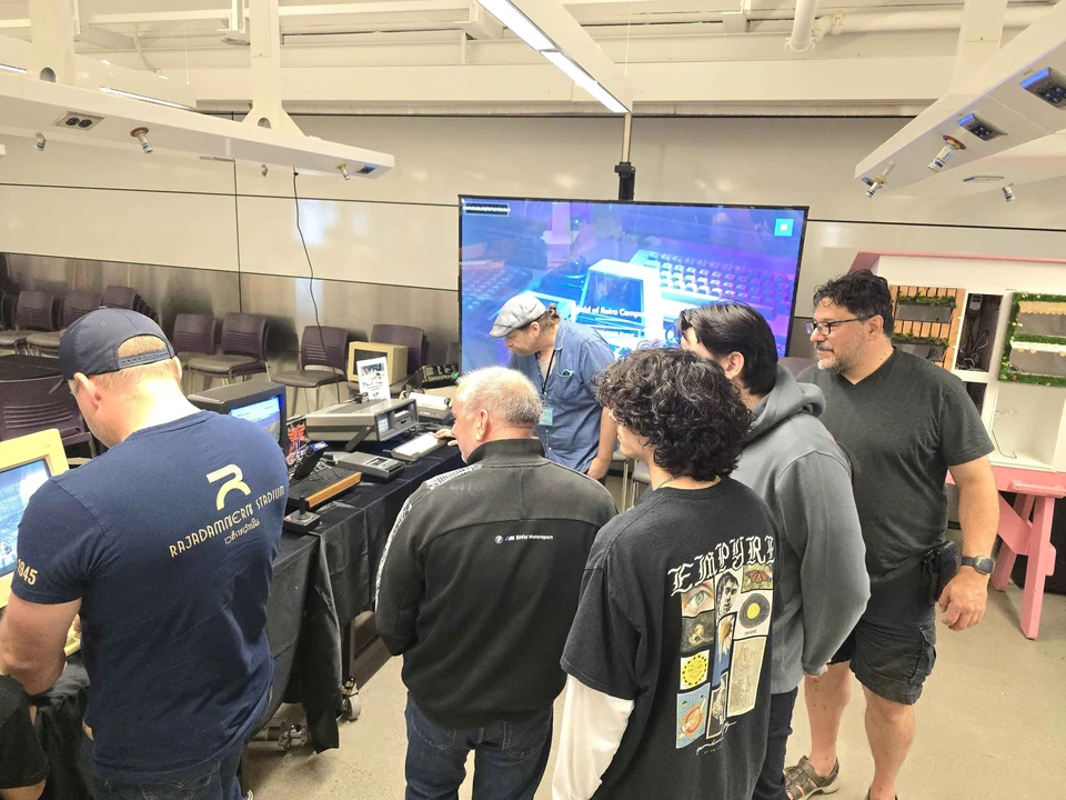 A group of visitors talking beside a computer demonstration at WoRC Expo 2026